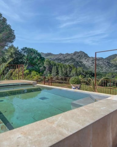 Swimming pool on terrace with metal railings overlooking forested mountains and valley