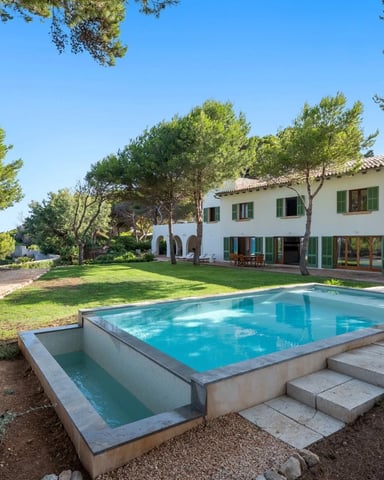 Mediterranean villa with swimming pool, green shutters, manicured lawn, pine trees, and sea view