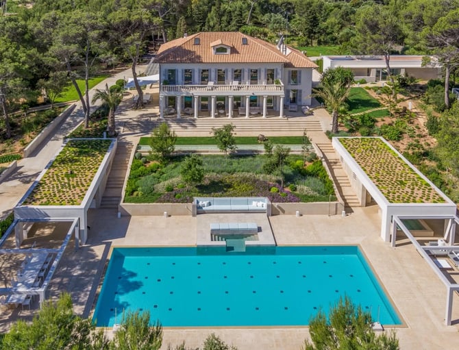 Aerial view of modern villa with terracotta roof, swimming pool, manicured gardens, and surrounding trees
